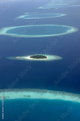 Blue and turqouise coral reef surrounding a small island, in the Maldives, aerial view, panorama from the air.  photo