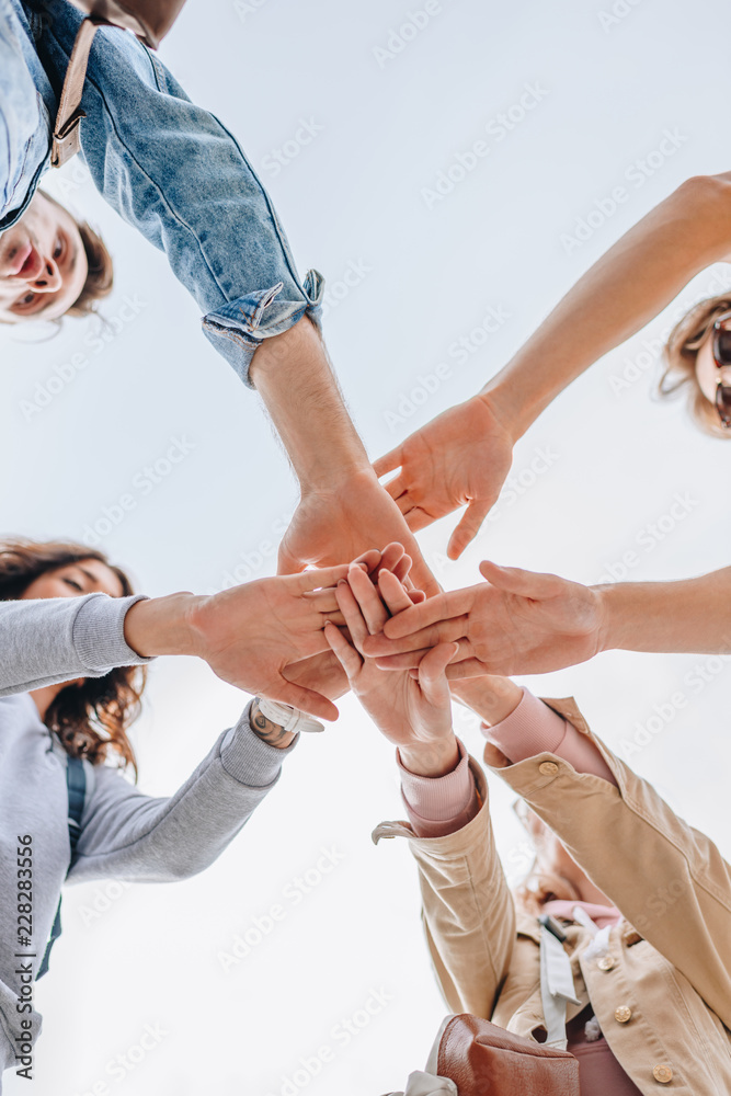 Obraz premium bottom view of young friends putting hands together