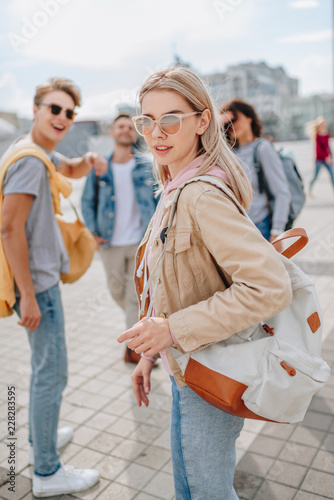 beautiful stylish woman walking in city with friends