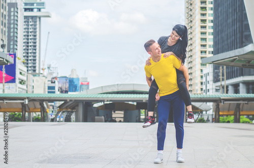 Happy sport man carrying his woman on back at the city background © TeTe Song