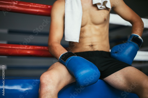 Male boxer in boxing gloves on ring background