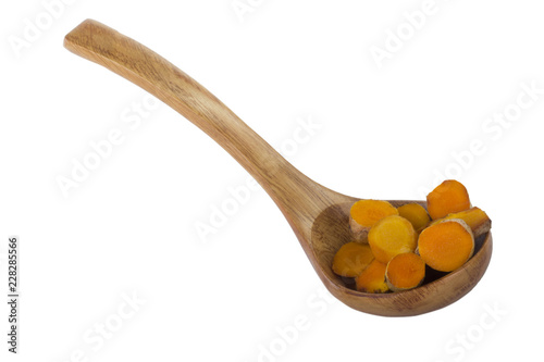 heap of slices of turmeric in wooden spoon isolated on white background