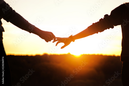 Romantic couple holding hands and watching a beautiful sunset