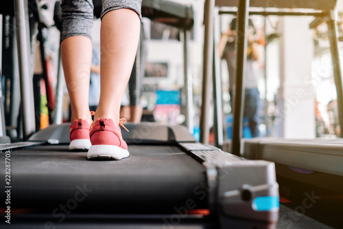 Scene in fitness gym. Sneaker shoe of sport girl exercise running on treadmill machine.