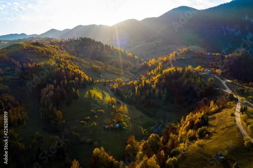 Beautiful sunset over the mountain forest in autumn season, October. Colors of the forest in the sunset light from above. Aerial view over the colorful forest of autumn season in the mountains. Magura