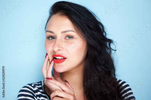 Close up portrait of young woman with red lips on blue background