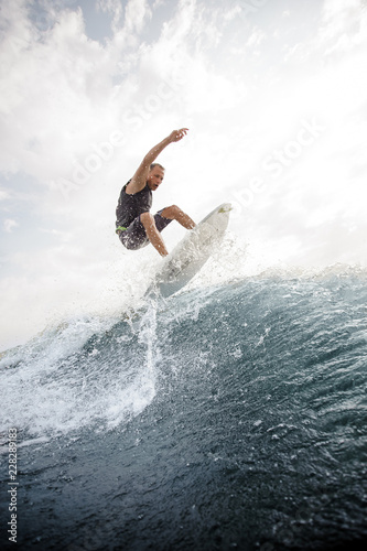 Man jumping on the white wakeboard down the blue water against grey sky