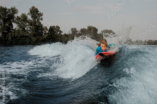 Active boy lying on wakeboard and swimming down the river