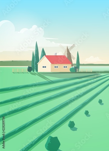 Vertical countryside landscape with agricultural building or house and plowed green field against windmill and sky with clouds on background