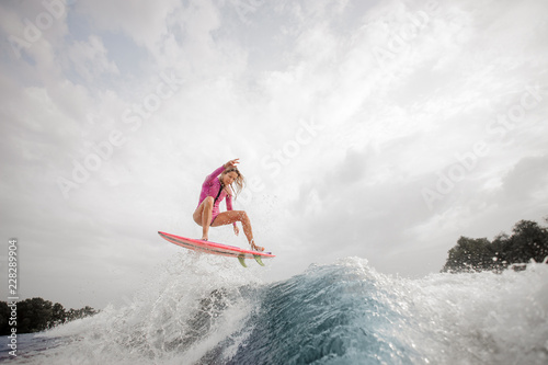 Teenager girl jumping on the orange wakeboard