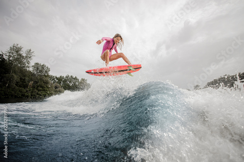 Active girl riding on the orange wakeboard