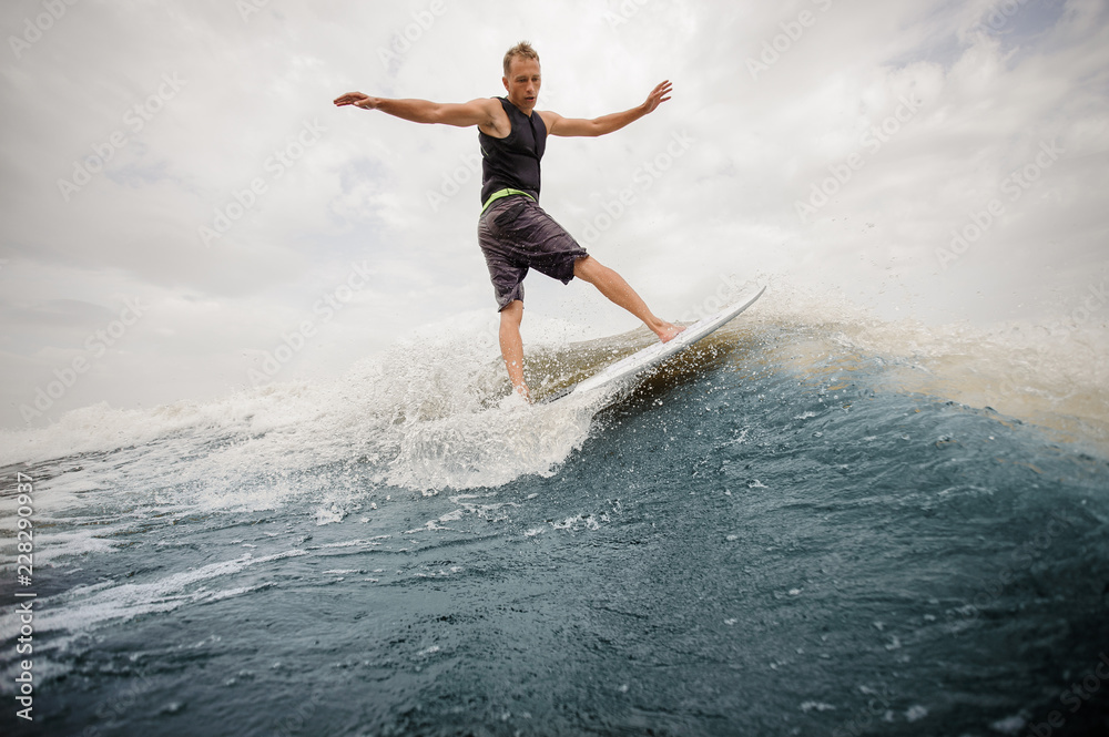 Rear view active man riding on the wakeboard