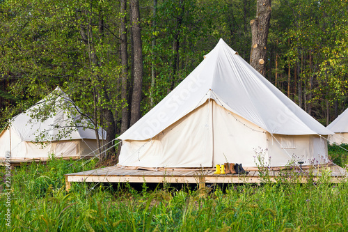 Two canvas bell tents outdoors at forest