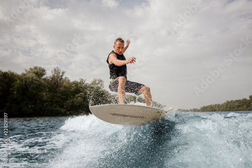 Active man jumping on the wakeboard on the high wave