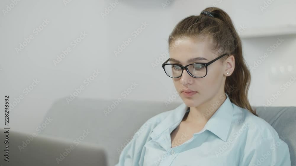 Portrait of teenage student girl in glasses is using a laptop at home, typing on notebook, preparing for exams or homework at home Portrait of teenage student girl in glasses is using a laptop at home, typing on notebook, preparing for exams or homework at home