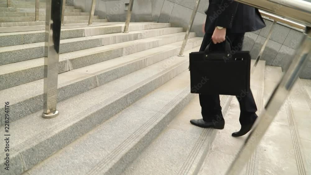 Close crop of businessman feet walking in city (steadicam shot, slow motion) Close crop of businessman feet walking in city (steadicam shot, slow motion)