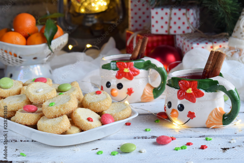 Obraz premium Christmas and new year holiday celebration concept background. Mug of mulled wine with spices, homemade nut cookie, shortbread, xmas tree decoration on wooden table.