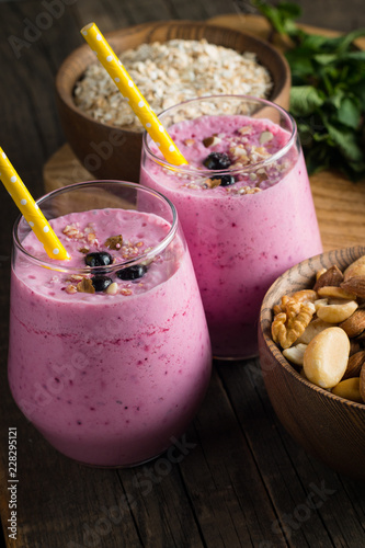 Glasses of berry smoothie with nuts, mint, blueberry, blackberry, raspberry, and yogurt on wooden table. Weight loss and diet concept. 