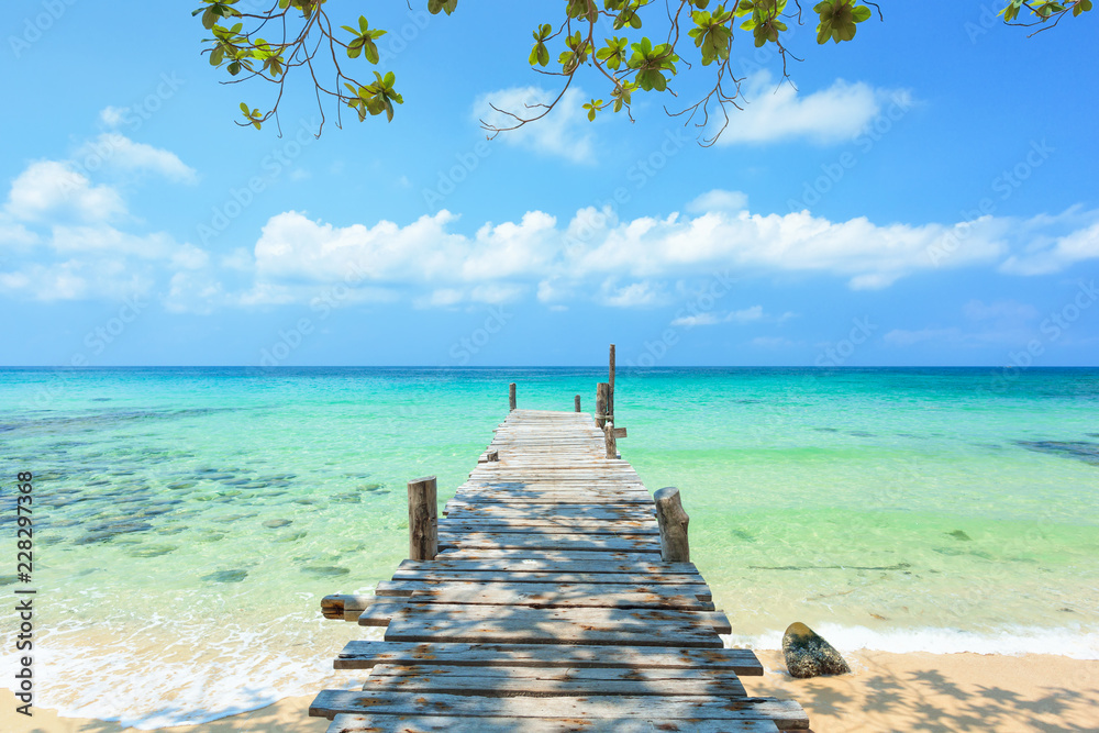 Fototapeta premium Długi drewniany most prowadzi nad morze na pięknej tropikalnej wyspie Tajlandii.