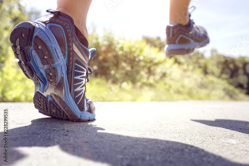 Feet of runner running or jogging on a road in summer