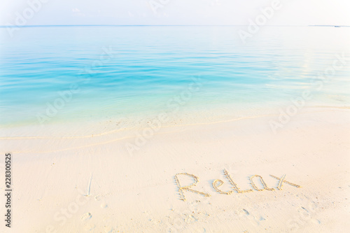 The Word Relax Written in the Sand on a Beach with morning sea background