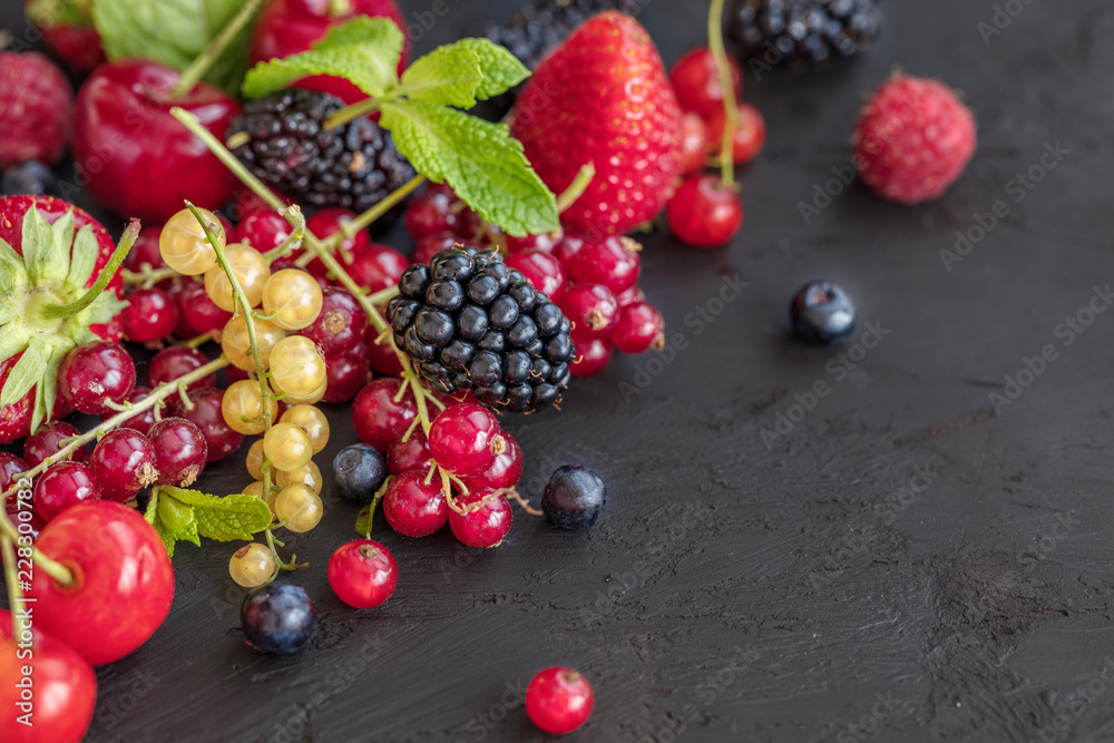 Mixed berries on a dark background with selected focus. Strawberries, Raspberries Blackberries, cherries, red and yellow currents. Healthy Living and Nutritious Food concept. Mixed berries on a dark background with selected focus. Strawberries, Raspberries Blackberries, cherries, red and yellow currents. Healthy Living and Nutritious Food concept.
