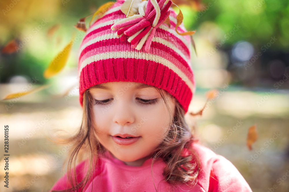 Beautiful little girl sitting in fallen leaves at autumn park Beautiful little girl sitting in fallen leaves at autumn park
