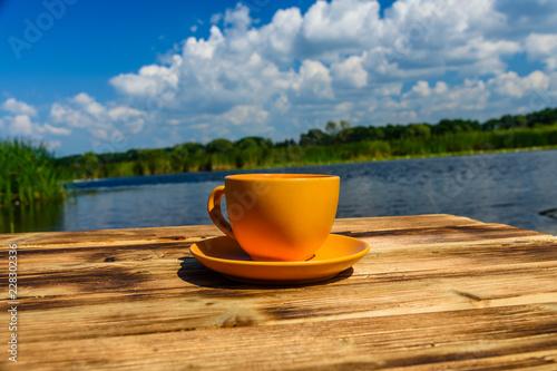 Cup of coffee on wooden table at the riverside