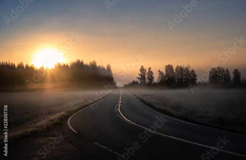 Scenic road landscape with sunrise and fog at autumn morning in Finland