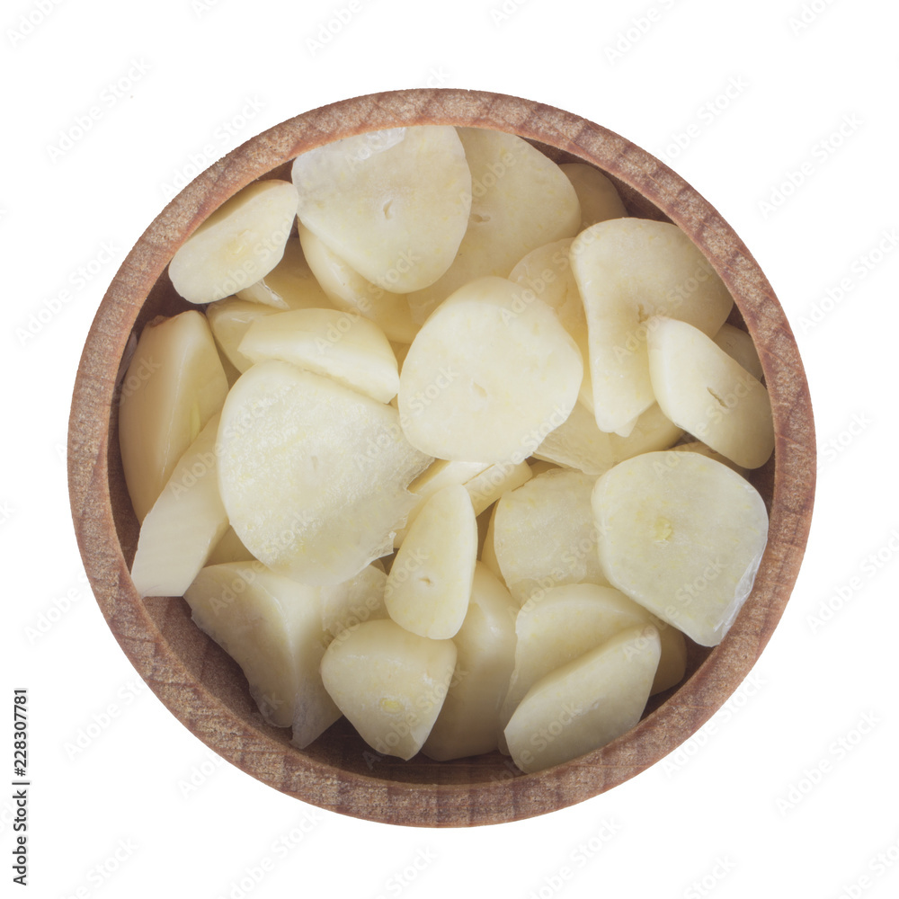 slices of garlic in wooden cup isolated on white background