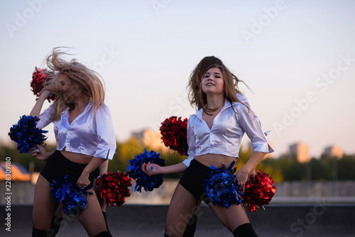 Cheerleaders dancing on the roof at sunset against the city landscape photo