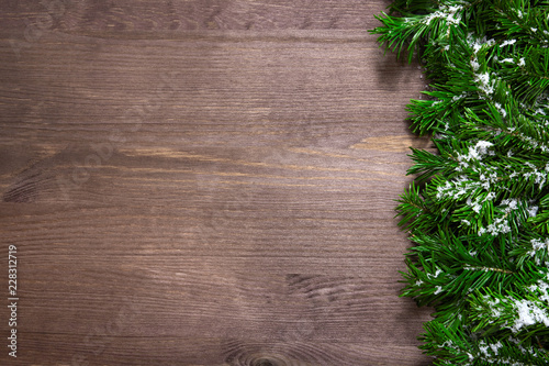 Christmas tree branches and snow on wooden background.
