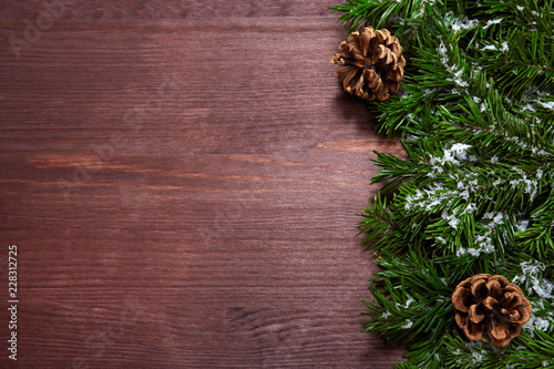Christmas tree branches and pine cones on wooden background. 