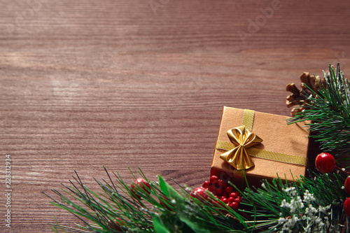 Fir tree branches, red berries and present box on wooden surface. Christmas and new year background.