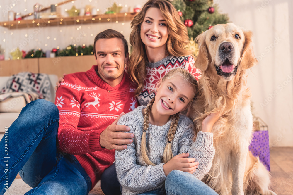 smiling family with golden retriever dog sitting near christmas tree with gifts smiling family with golden retriever dog sitting near christmas tree with gifts