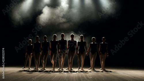 A very large group of children perform and dance on stage in the dark with smoke and concert lighting, they simultaneously bow at the end of the performance. Dancing. Ballet. photo