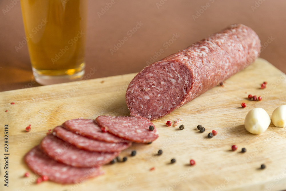 raw smoked sausage on a wooden chopping Board with spices a glass of beer raw smoked sausage on a wooden chopping Board with spices a glass of beer
