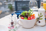 Fresh vegetable salad in a cup on the dining table. Ingredients for summer salad. Vitamins and benefits. Copy space.