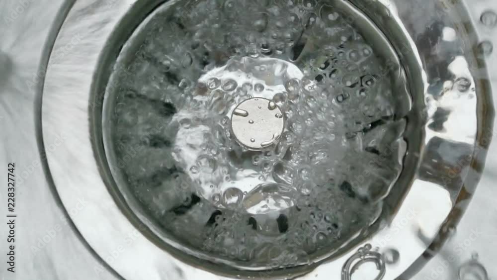 Stainless steel sink plug hole close up with water Stainless steel sink plug hole close up with water