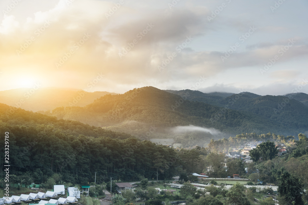 Mountain landscape with the sun, buildings in mountain village. Foggy day, Top view village landscape mist / Beautiful morning with fog over misty on village and mountain background on winter Mae Hong