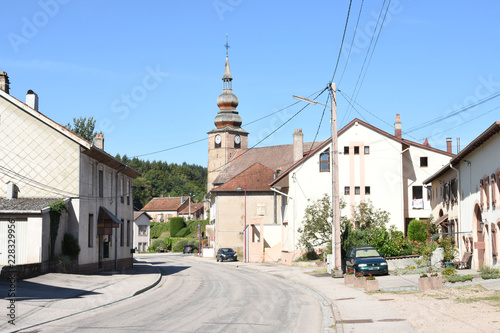 dorpsstraat met kerktoren en bovengrondse stroomleidingen in Provenchères-sur-Fave in de Vogezen