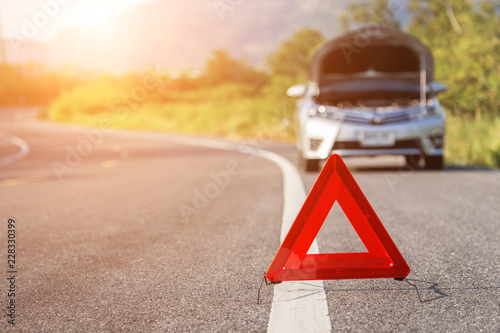 Red emergency stop sign and broken car on the road