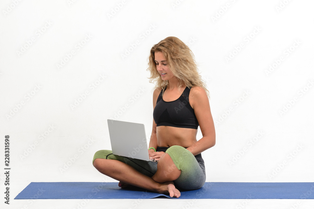 Beautiful young woman doing yoga with laptop on white background Beautiful young woman doing yoga with laptop on white background