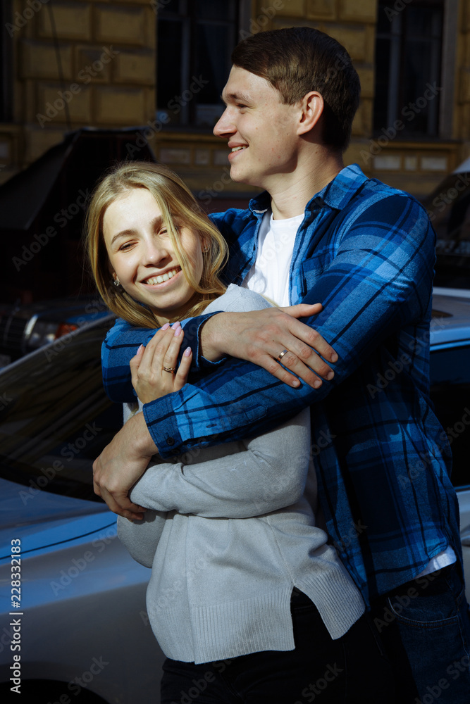 Obraz premium Portrait of a happy couple hugging in the street, in the city.standing in better from the sun, hard light. date
