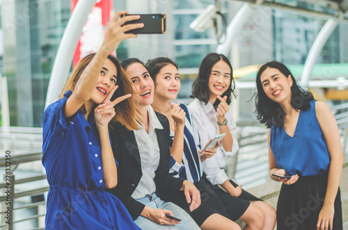 Four happy Asian businesswoman colleague taking selfie with smartphone in city,looking at camera, happy healthy diverse fit people relaxing after working out together in office.