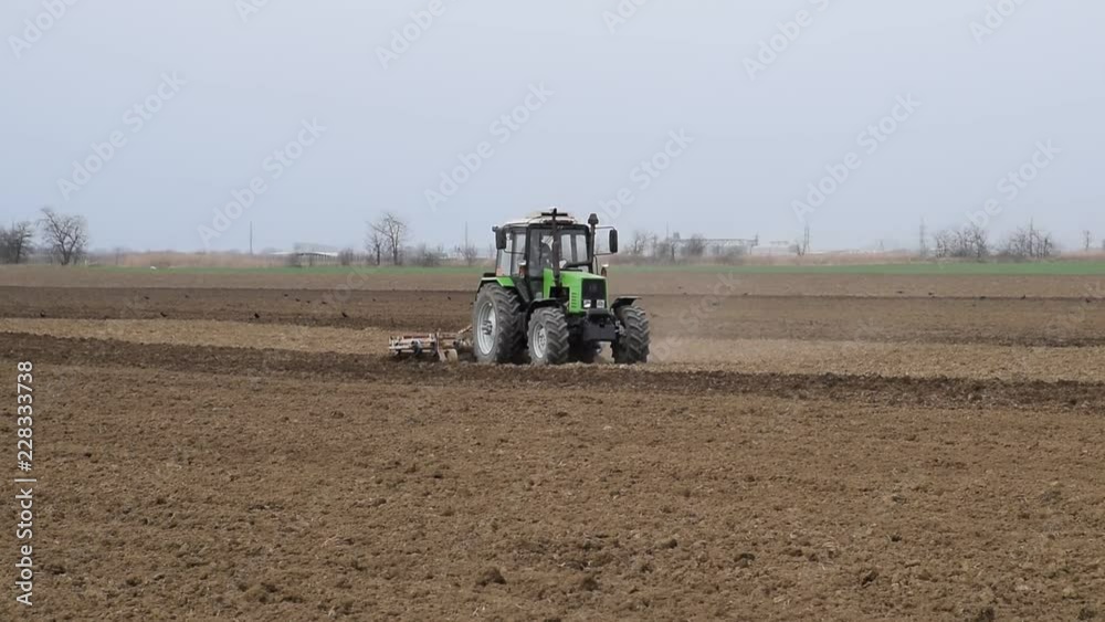 Lush and loosen the soil on the field before sowing. The tractor plows a field with a plow Lush and loosen the soil on the field before sowing. The tractor plows a field with a plow