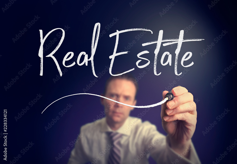 A businessman writing a Real Estate concept with a white pen on a clear screen. A businessman writing a Real Estate concept with a white pen on a clear screen.