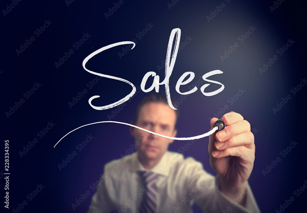 A businessman writing a Sales concept with a white pen on a clear screen. A businessman writing a Sales concept with a white pen on a clear screen.