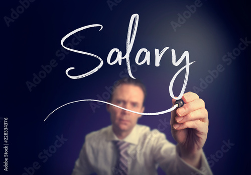 A businessman writing a Salary concept with a white pen on a clear screen.