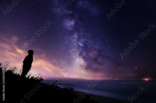 Silhouette of a lonely man watching the stars and the Milky Way over the sea in Tuscany